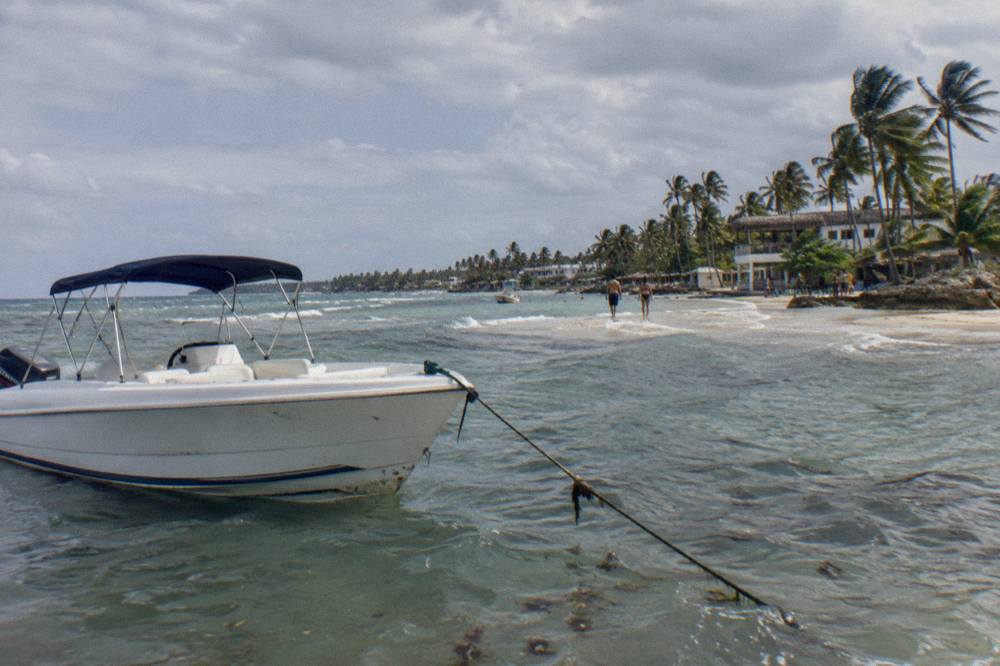 A white speedboat anchored in shallow turquoise water beside a sandbar