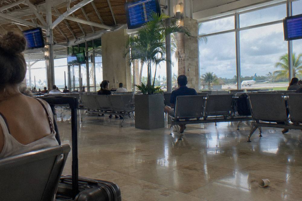 Departure hall waiting area with rows of seats and flight information boards above the counters