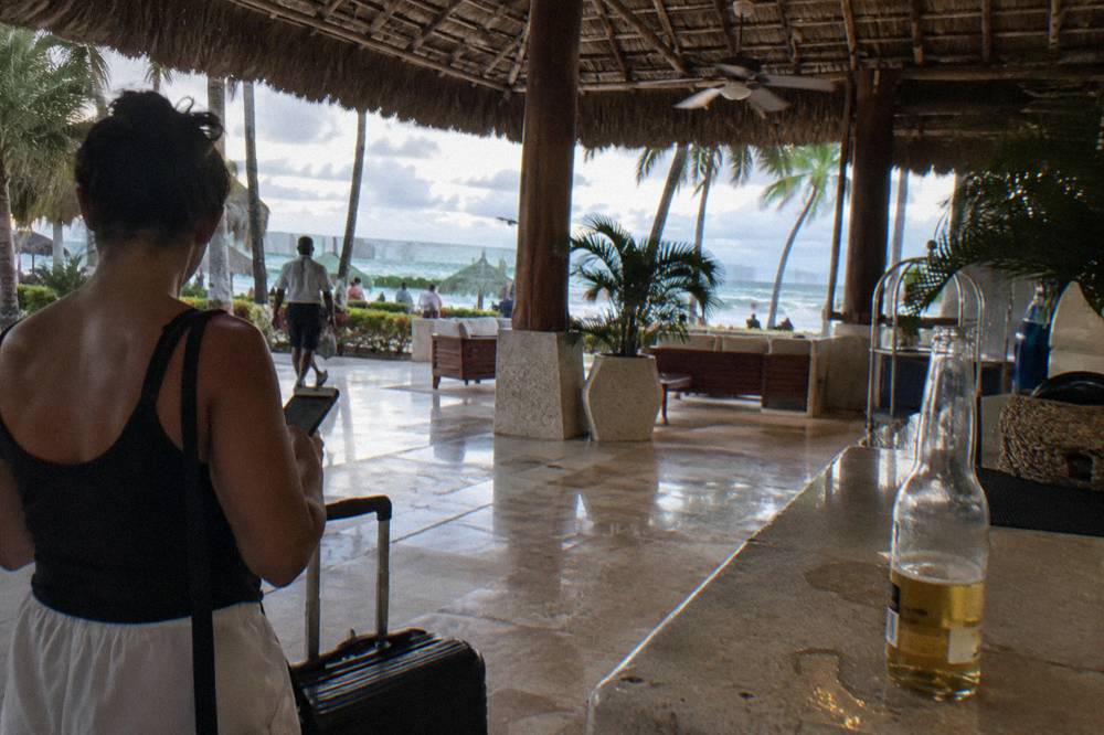 Traveler holding a phone displaying a QR code beside a suitcase in a hotel lobby