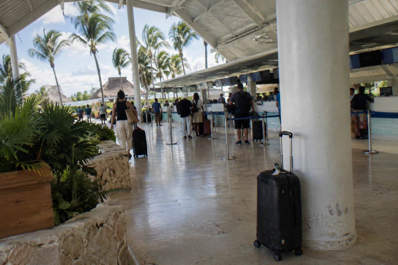 Airline check-in counters in a bright open-air terminal with palm trees visible through the glass