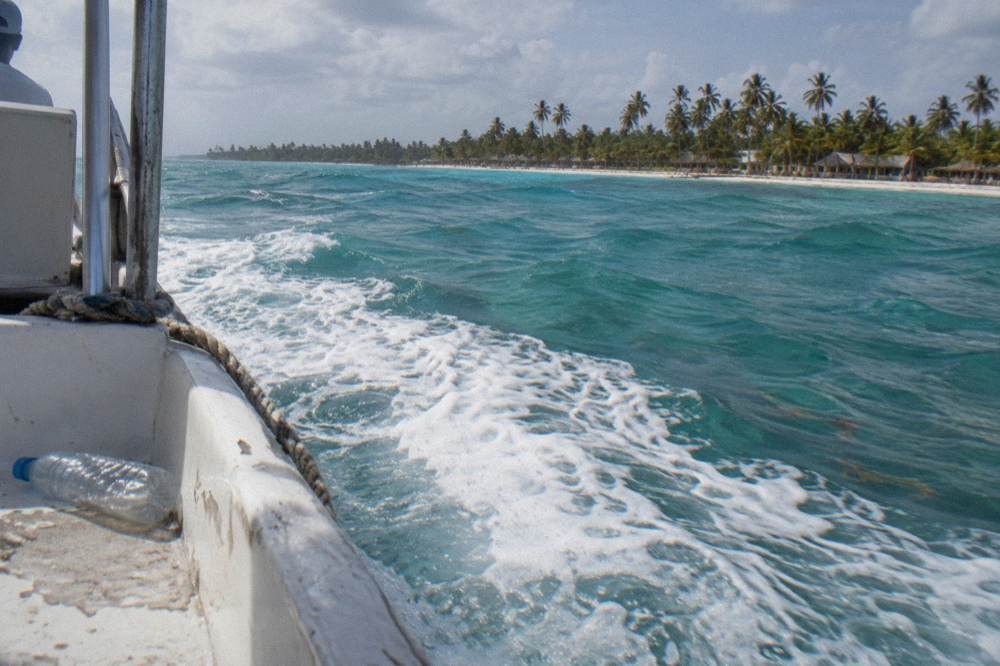 A white speedboat cutting across open turquoise Caribbean water