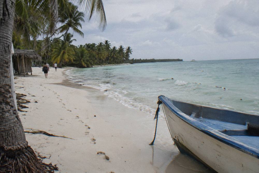 A white sand beach with calm turquoise water and a line of palm trees