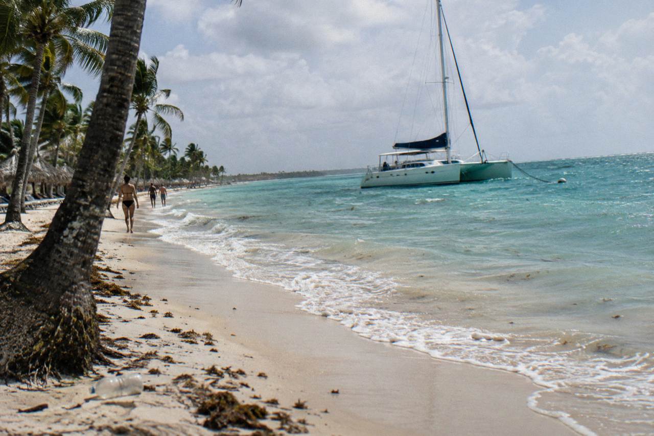 Palm-lined beach in Punta Cana with calm turquoise water and an anchored catamaran