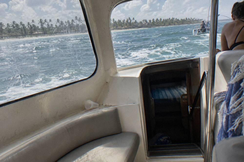 The enclosed deck cabin of a day-trip catamaran with seating and a companionway leading below