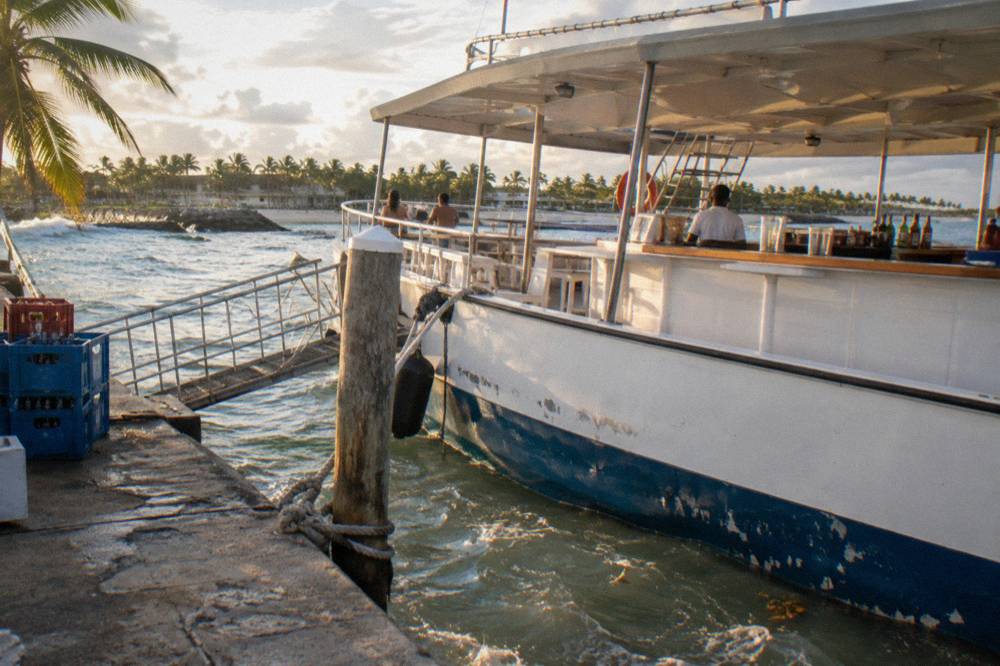 An open-deck party boat with a bar counter and railings along the side, moored at a marina