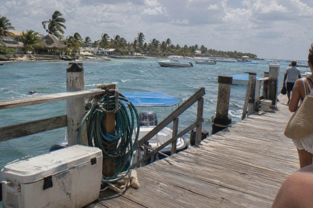 A wooden pier at a Caribbean marina with boarding stairs down to moored boats