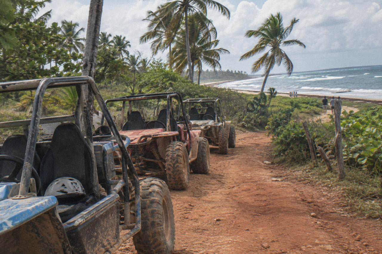 Dune buggies parked on a dusty trail near palm trees in the Dominican countryside