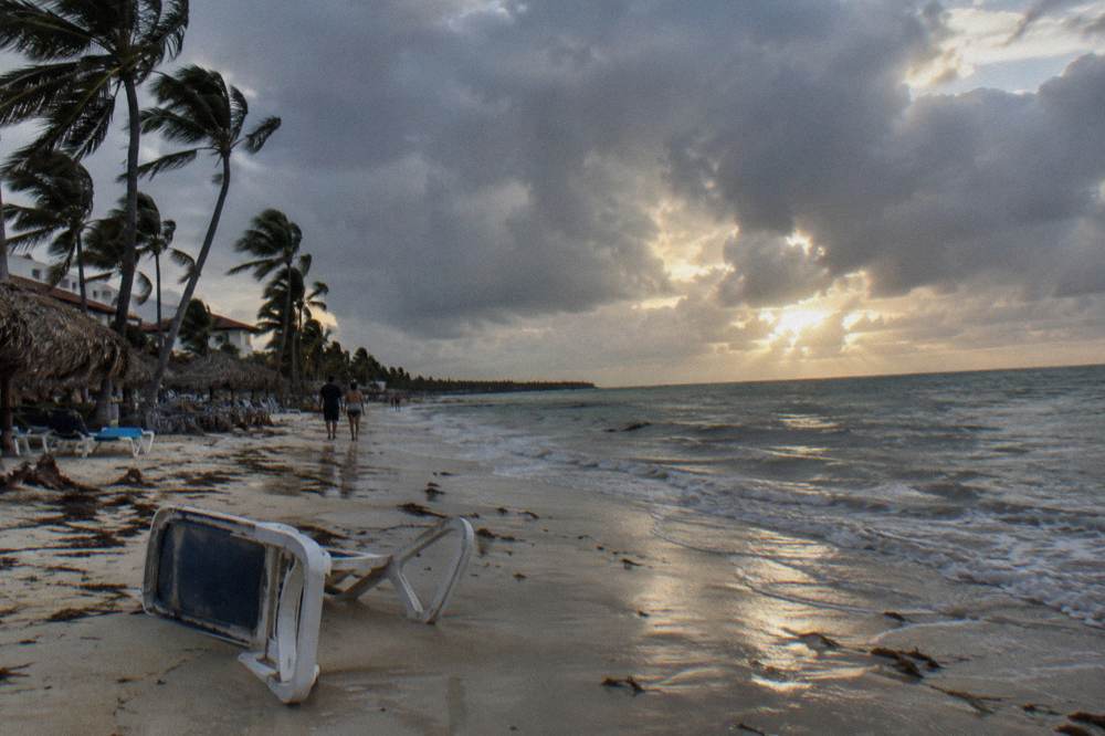 Dramatic tropical sky with sunlit clouds over a calm resort beach and calm water
