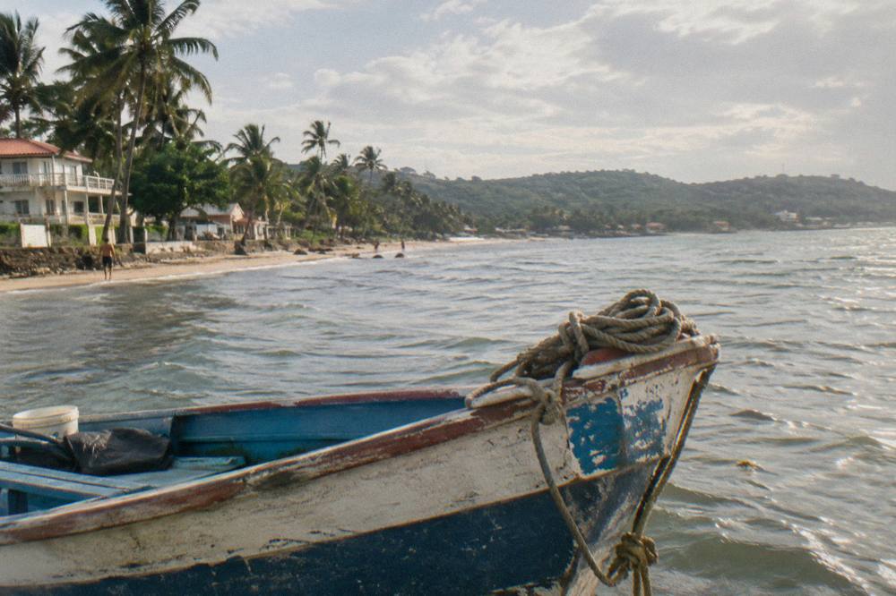 Wooden boat resting in a quiet tropical bay surrounded by green hills