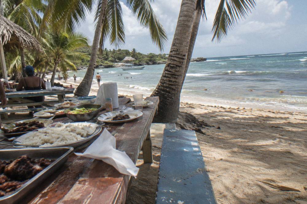 Wooden tables set for lunch under palm trees on a small island beach