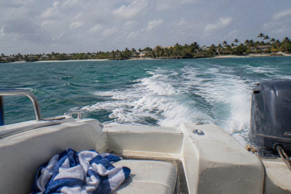 Speedboat crossing open turquoise water toward a green island shoreline