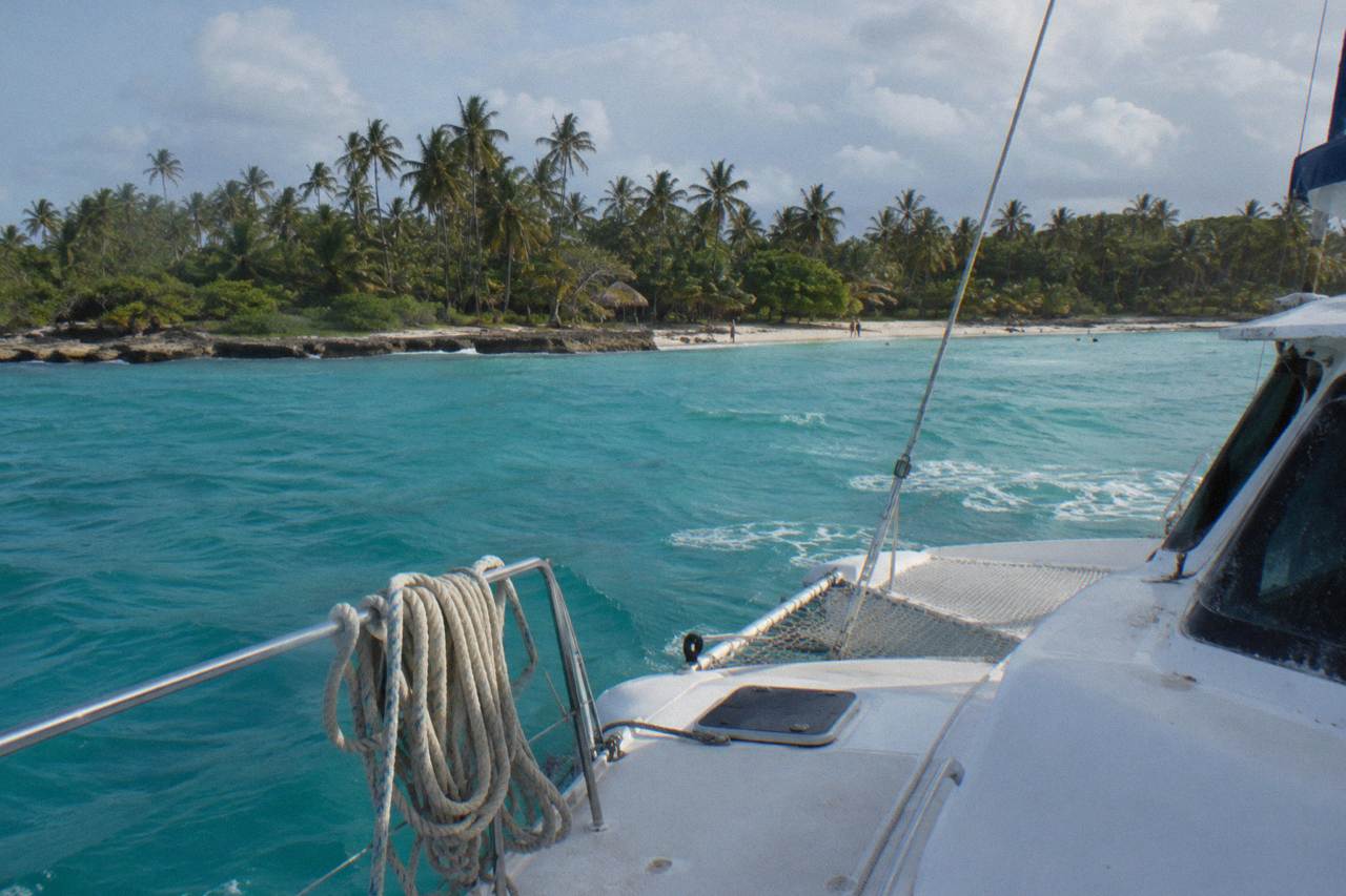Catamaran anchored off a small tropical island with palm trees and clear turquoise water