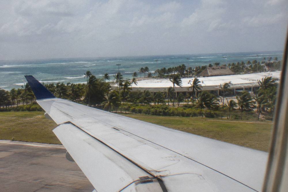 Palm-fringed runway edge seen from an airplane window on approach to a Caribbean airport