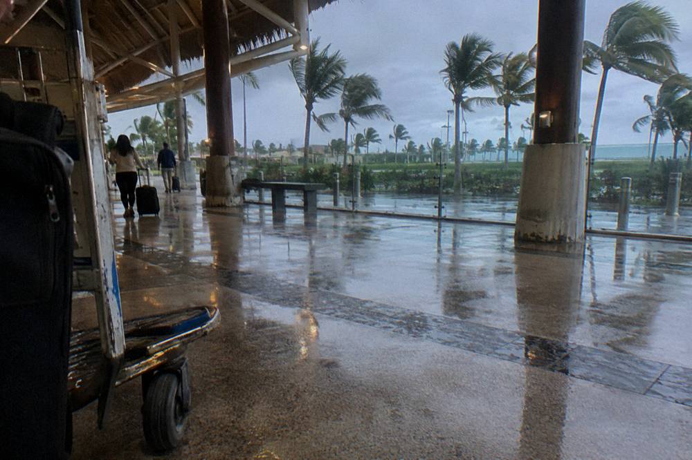 Tropical departure hall with open-air walkway and palm trees outside the glass wall