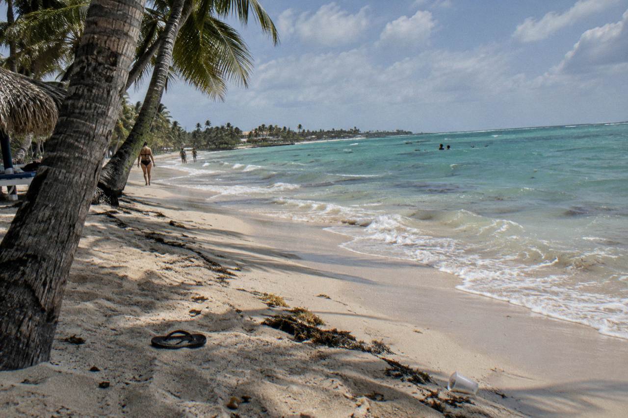 Wide sandy beach in Punta Cana with palm trees leaning over calm turquoise water