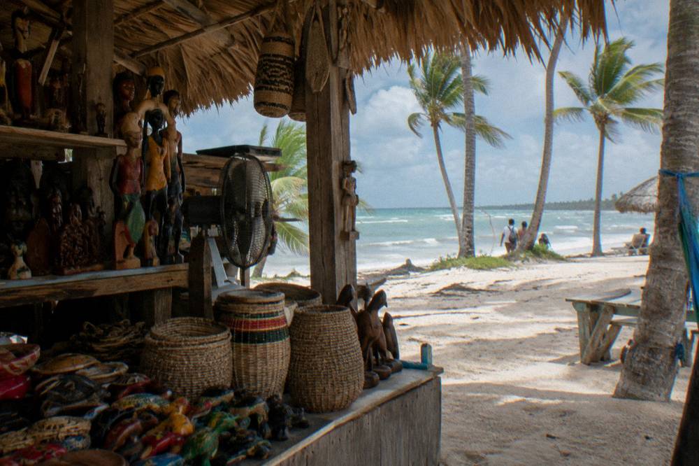 Open-air beach market stall with colorful souvenirs and shaded walkway