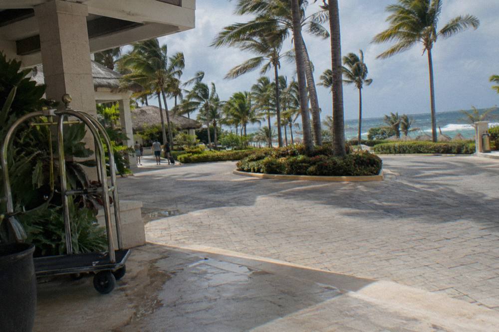 Resort hotel entrance with palm trees along a paved road in Bávaro