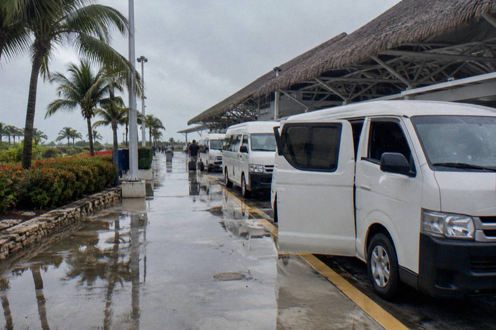 Row of waiting transfer vans parked outside an airport terminal building