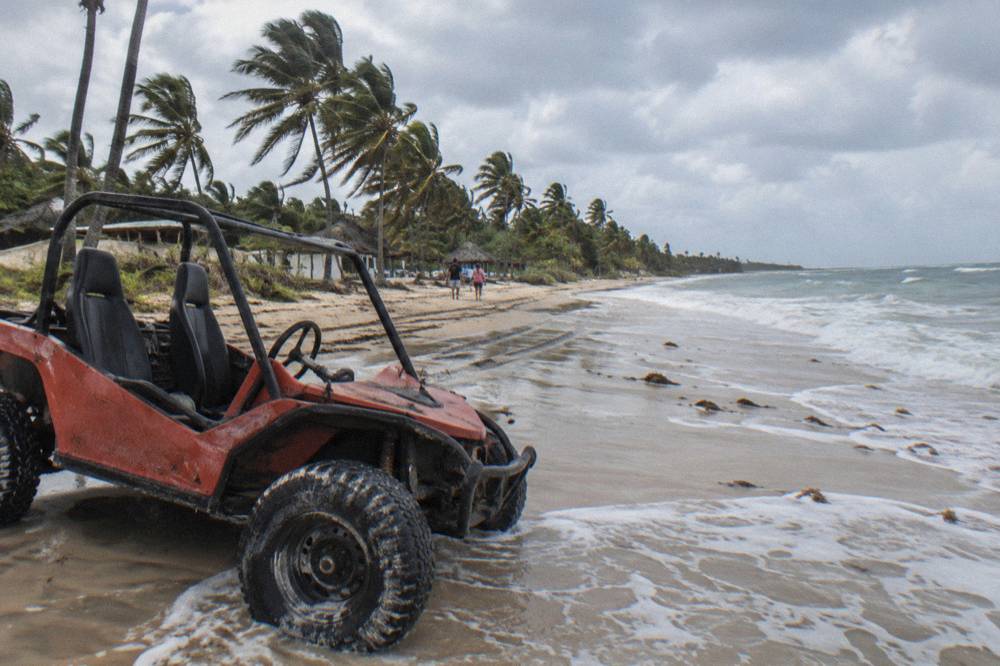 Two-seat dune buggy parked on wet sand at a wide open beach