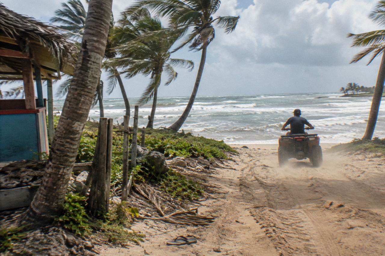ATV riding along a dusty trail toward a palm-lined beach in Punta Cana