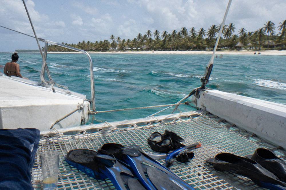 A catamaran deck with snorkel equipment laid out and clear water beyond the bow