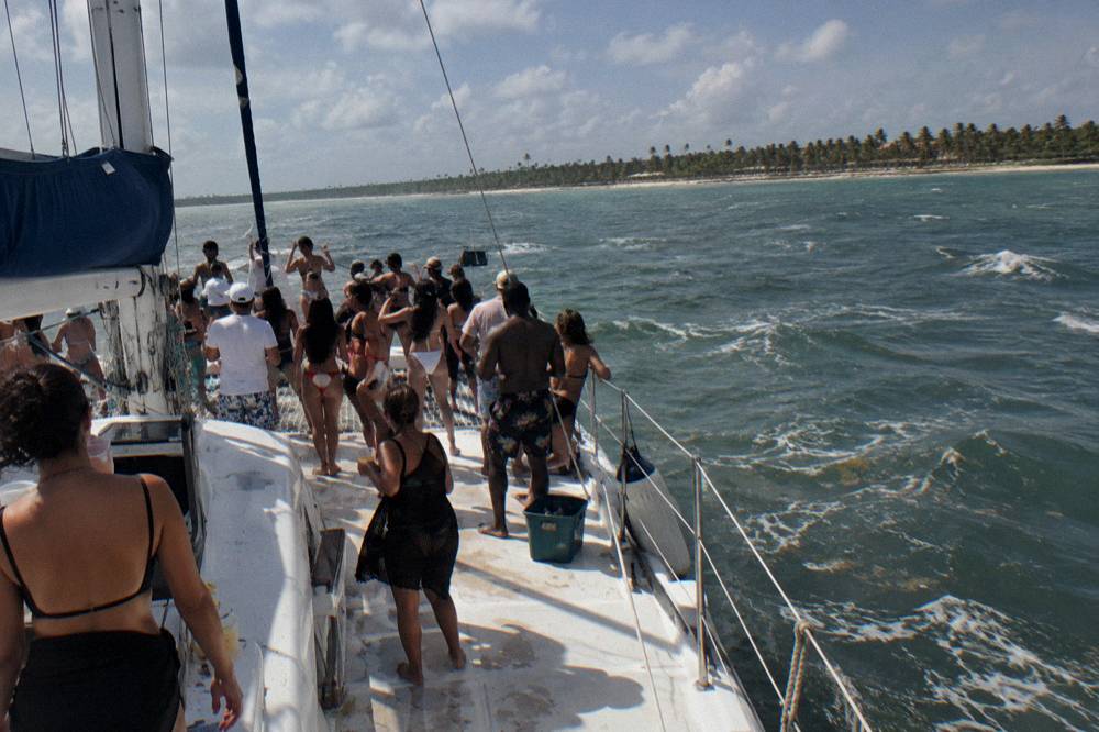 A crowded party catamaran with music and dancing in open water