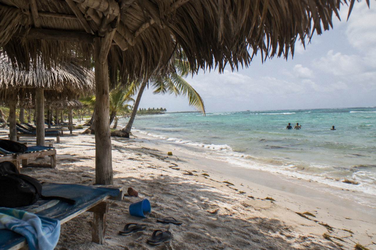 Shaded beach palapas along calm turquoise water on a Caribbean island day trip