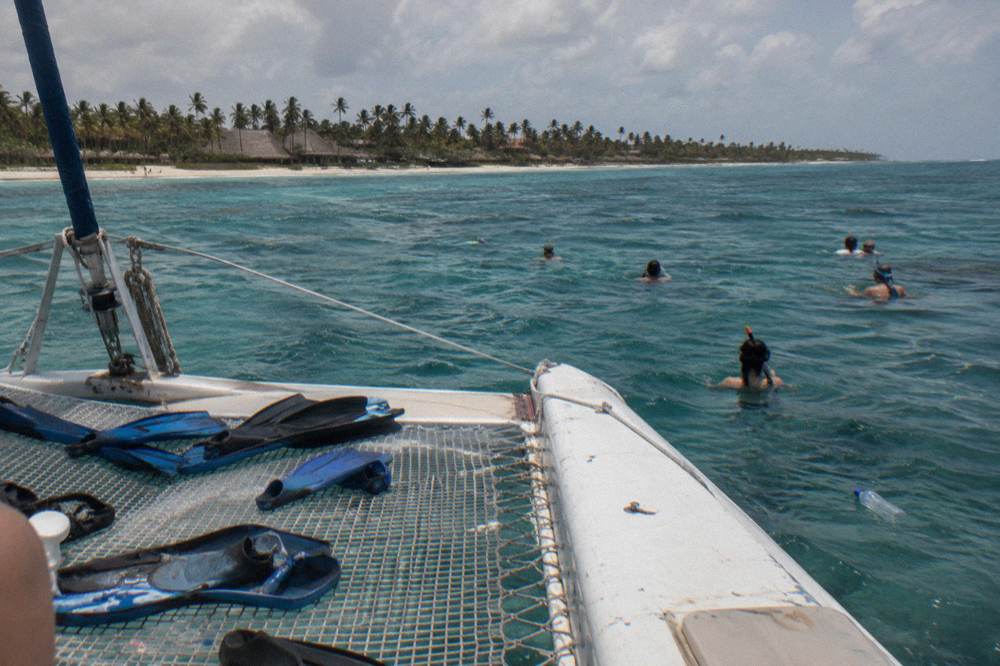 Catamaran anchored over a shallow reef with snorkelers in the water beside it