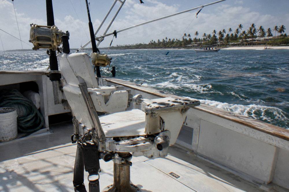 Fighting chair and outrigger on the deck of a sportfishing boat under a clear sky