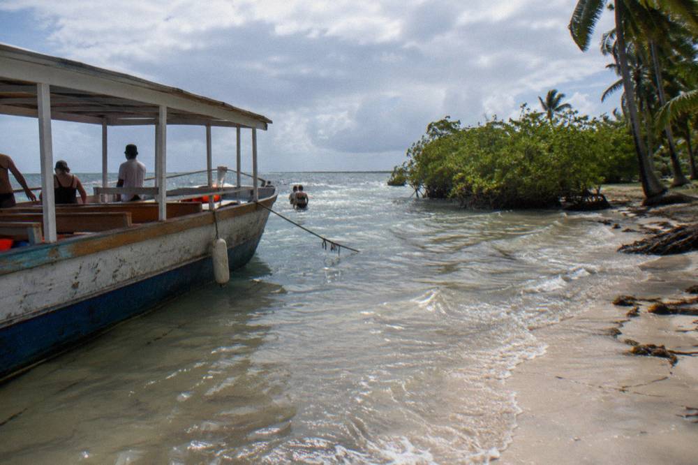 A catamaran anchored in shallow clear water near Saona Island under clearing skies
