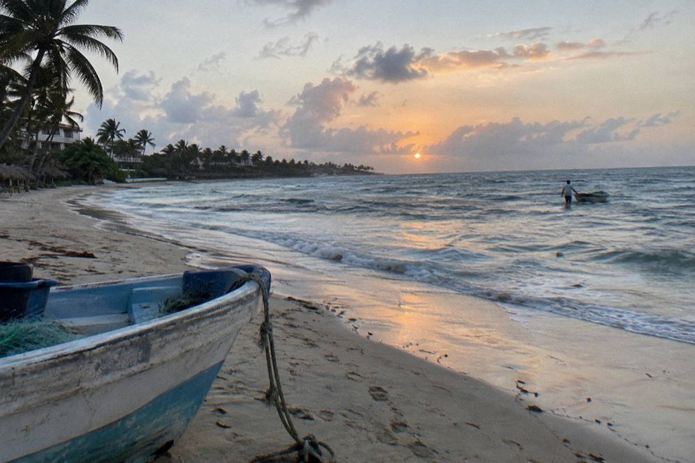 A calm sunrise over the Caribbean Sea seen from a Punta Cana beach with scattered clouds