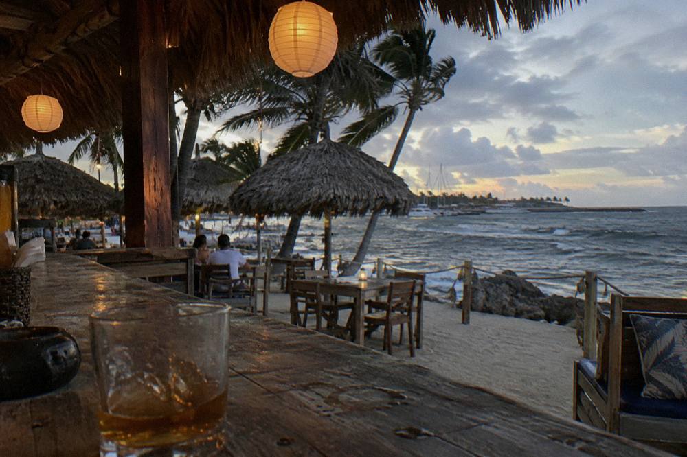 Beach bar deck with lanterns lit and the ocean dark beyond at nightfall
