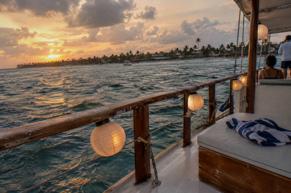 Catamaran deck at sunset with lanterns lit and a calm sea beyond the railing