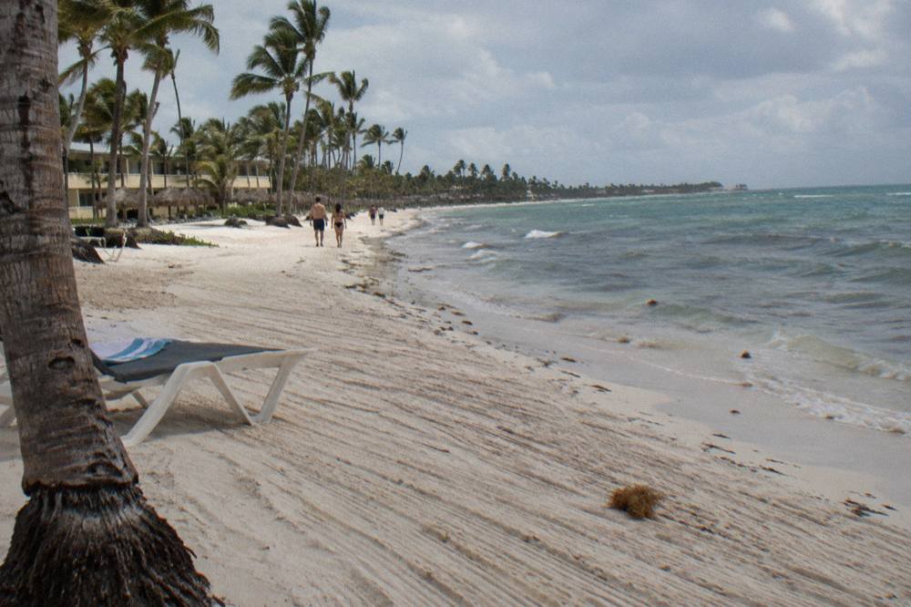 A sandy beach with raked sand in the morning and clear shallow water beyond