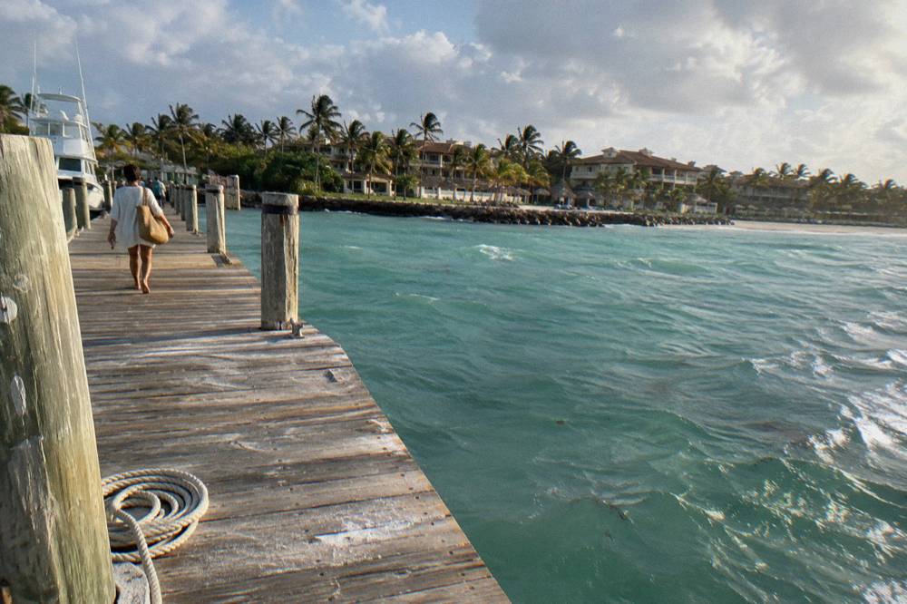 A wooden pier extending over calm green blue water with no seaweed visible