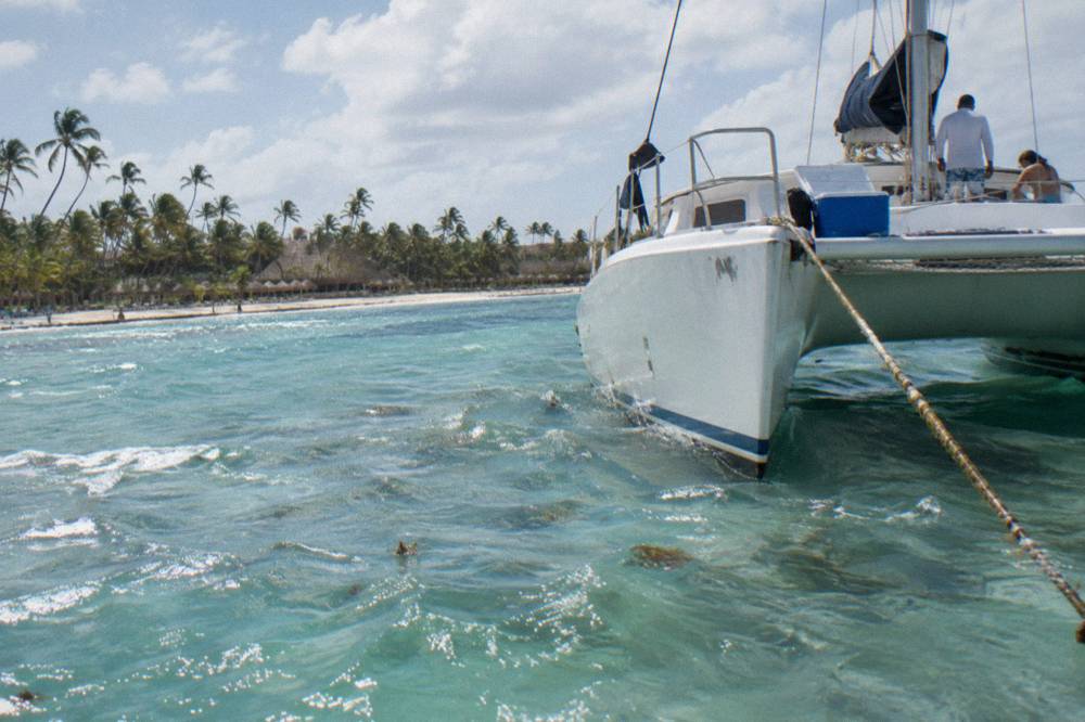 A catamaran anchored over pale turquoise water near a coral reef