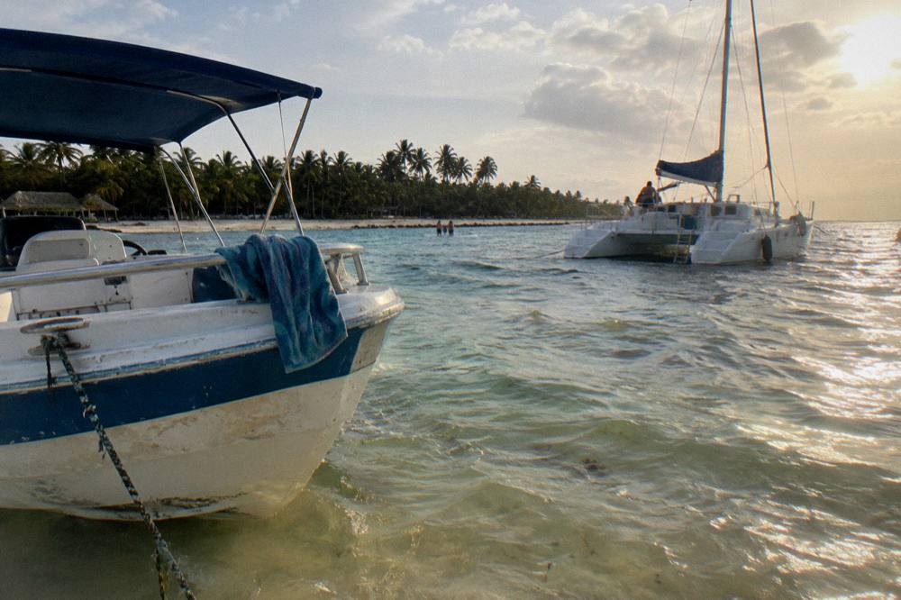 A speedboat and catamaran moored beside a shallow sandbar lagoon