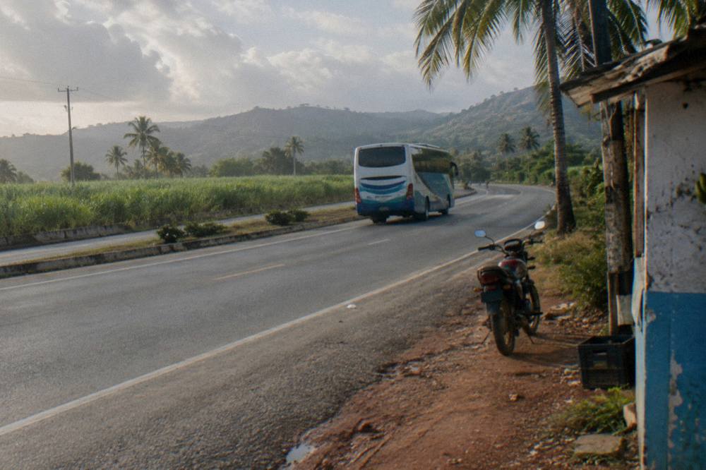 A touring bus on a highway through green hills in the Dominican Republic countryside
