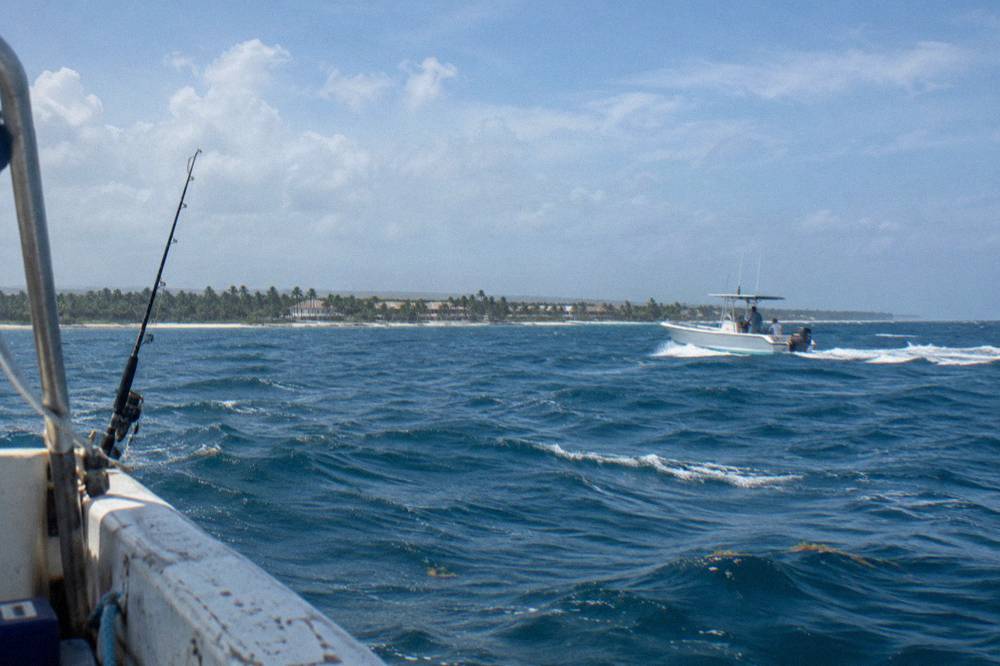 A fishing boat cruising over deep blue open water far from shore