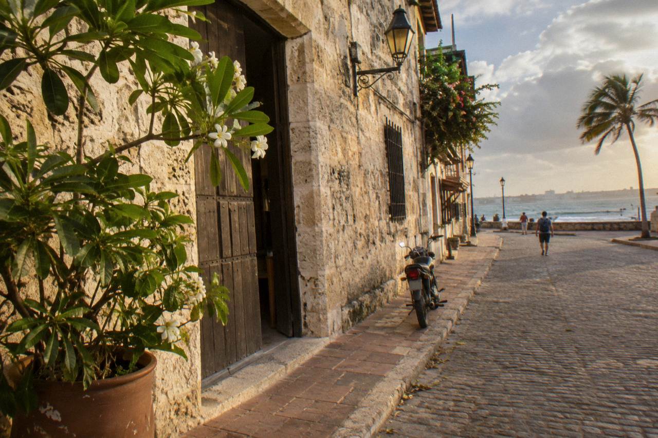 Colonial stone buildings and a quiet cobblestone street under a warm afternoon sky