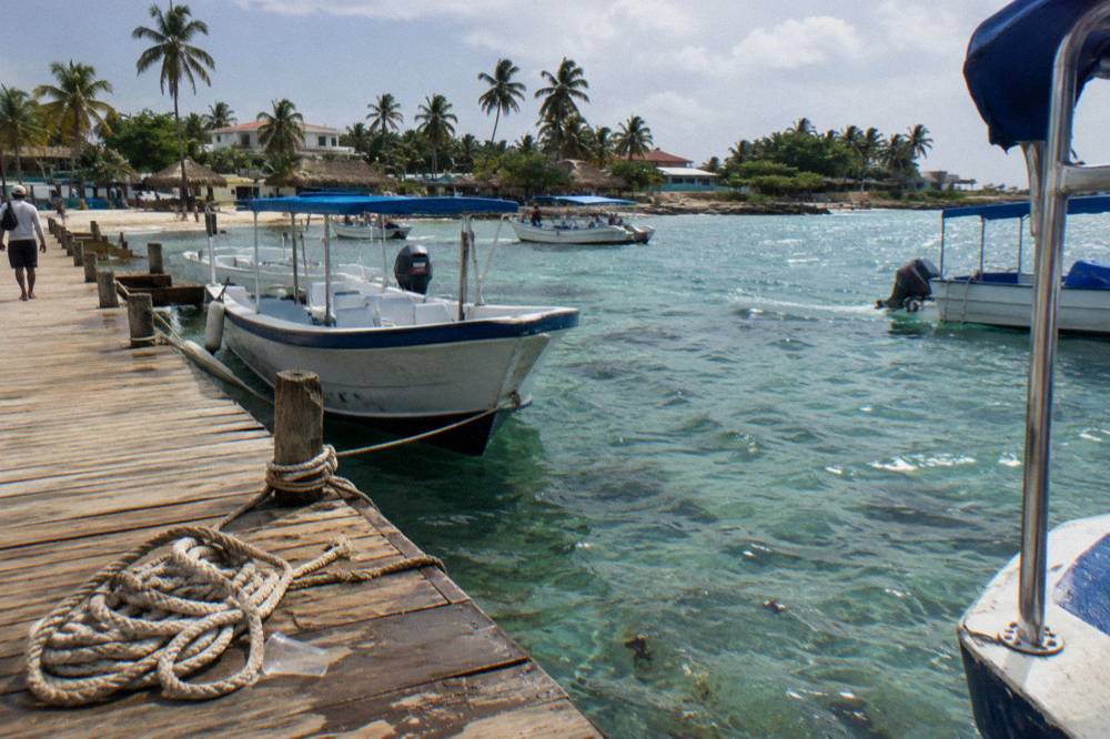 Wooden pier at Bayahibe with excursion boats moored over clear shallow water